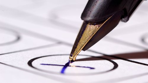 Fountain pen makes a cross on a piece of paper